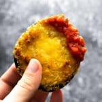 hand holding air fried eggplant dipped in marinara sauce