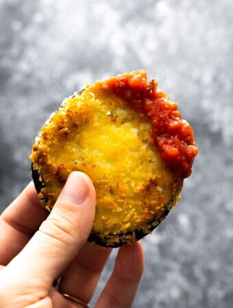 hand holding air fried eggplant dipped in marinara sauce