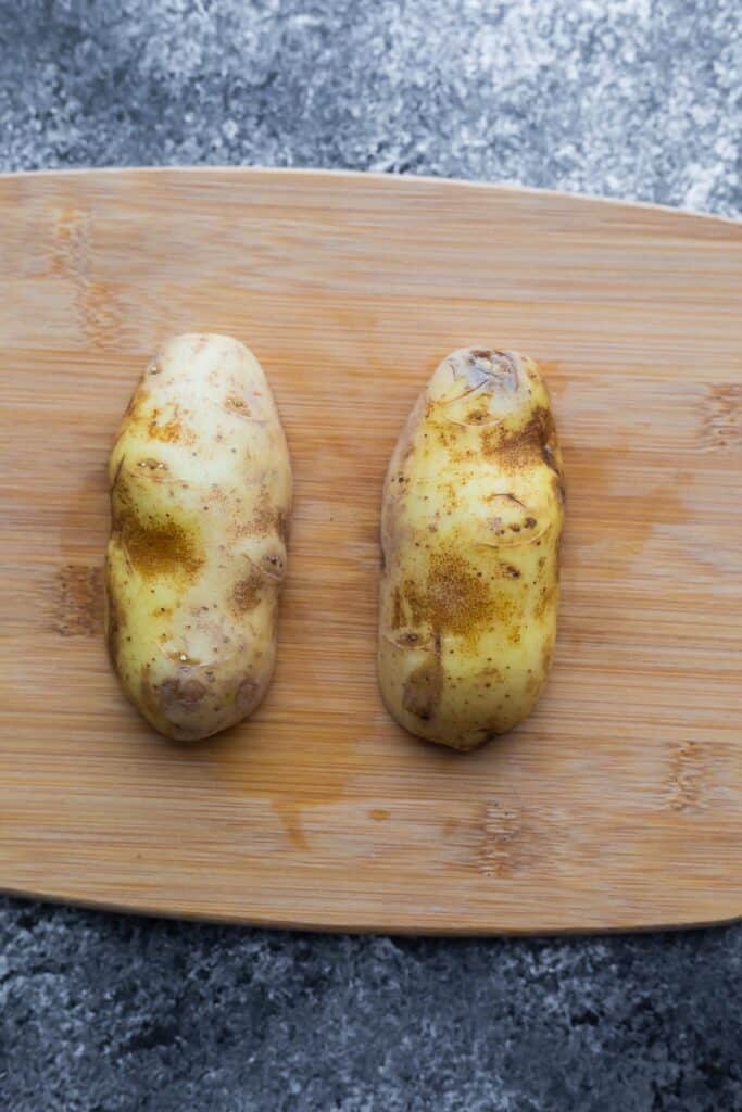 russet potato cut in half (cut sides down) on cutting board