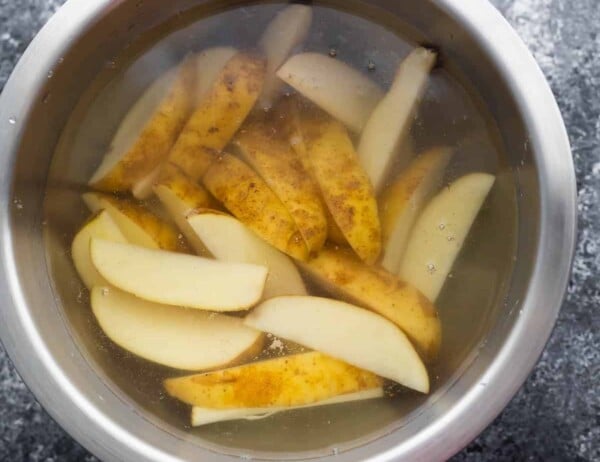 potato wedges soaking in bowl of water