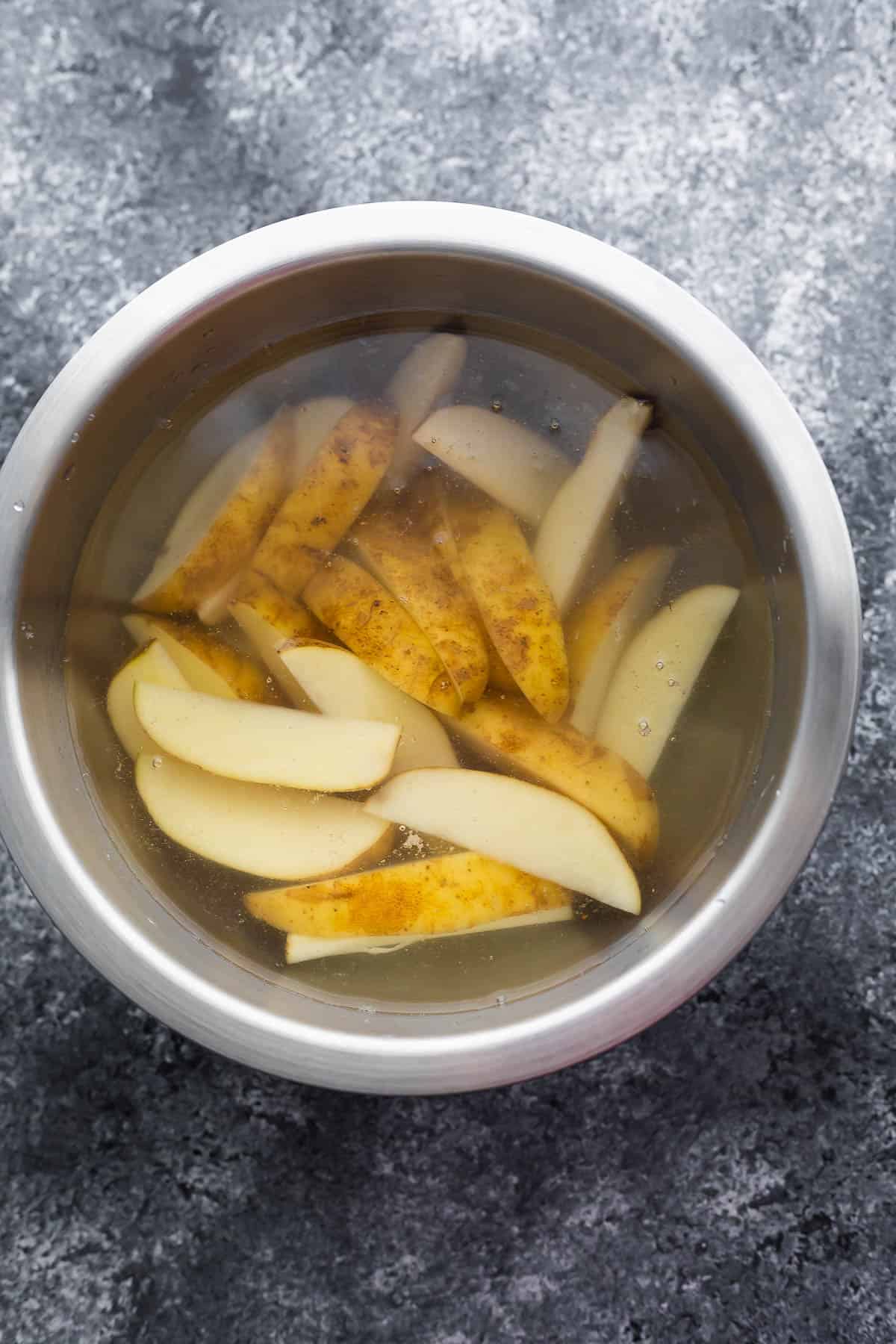 potato wedges soaking in bowl of water