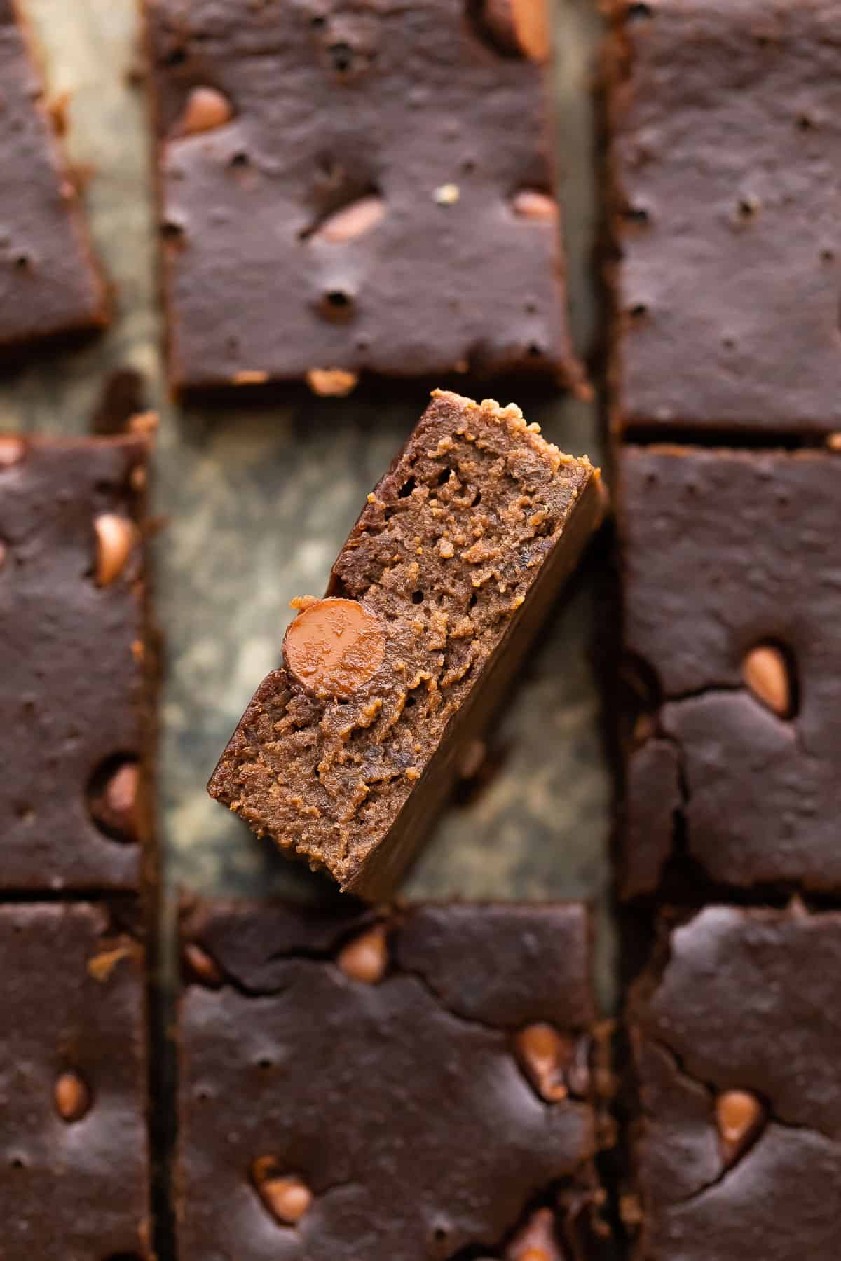 overhead view of black bean brownies with one on its side to reveal texture