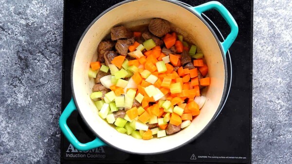 onions, celery and carrot added to beef in a pot