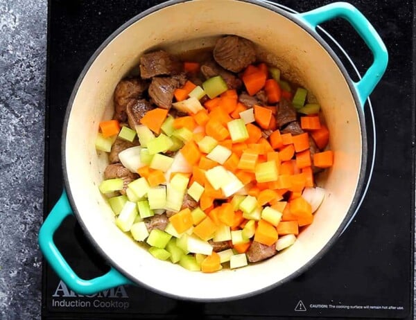 onions, celery and carrot added to beef in a pot