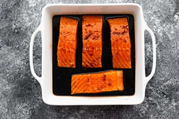 4 salmon fillets (unbaked) arranged in square baking dish with teriyaki sauce