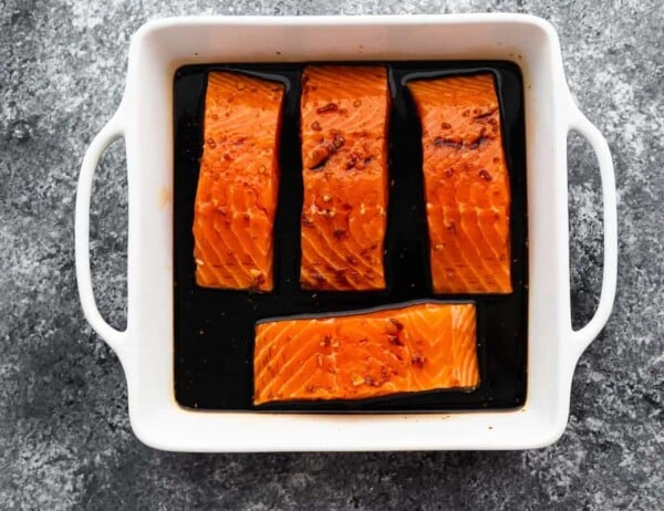 4 salmon fillets (unbaked) arranged in square baking dish with teriyaki sauce