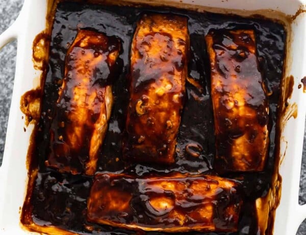 four baked salmon fillets arranged in baking dish with thickened teriyaki sauce