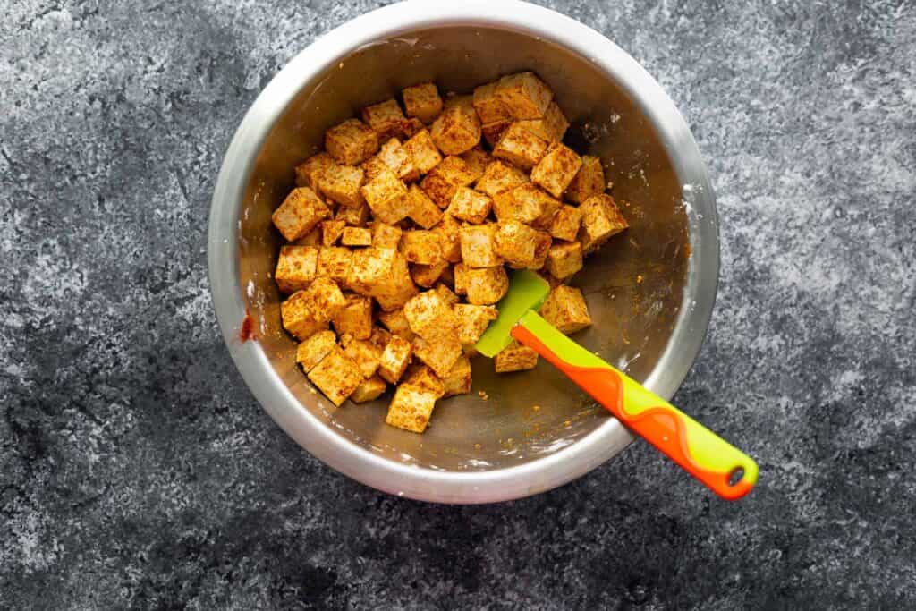 tofu tossed in oil and seasonings in a bowl