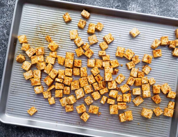 tofu cubes tossed in seasoning and spread out on baking sheet