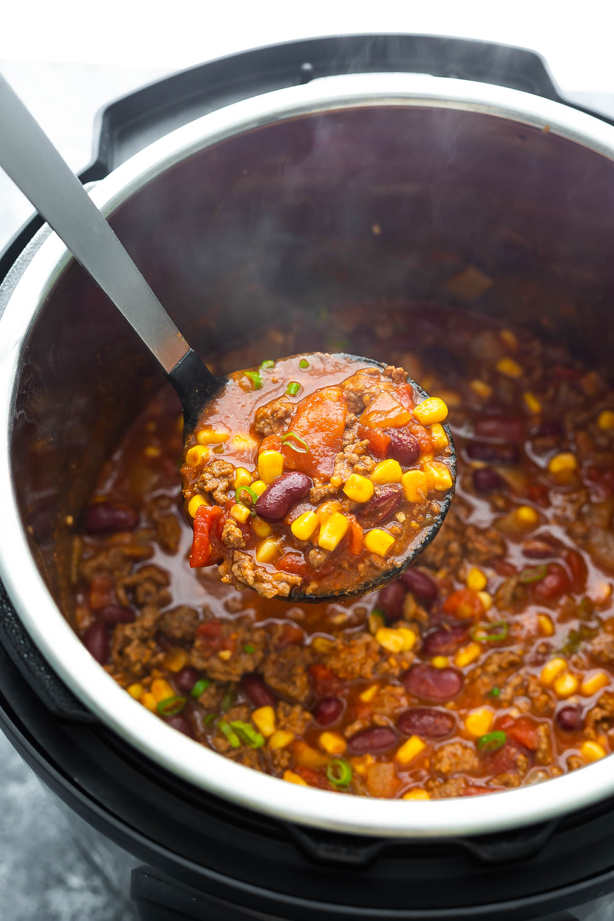 beef chili scooped on soup ladle above instant pot