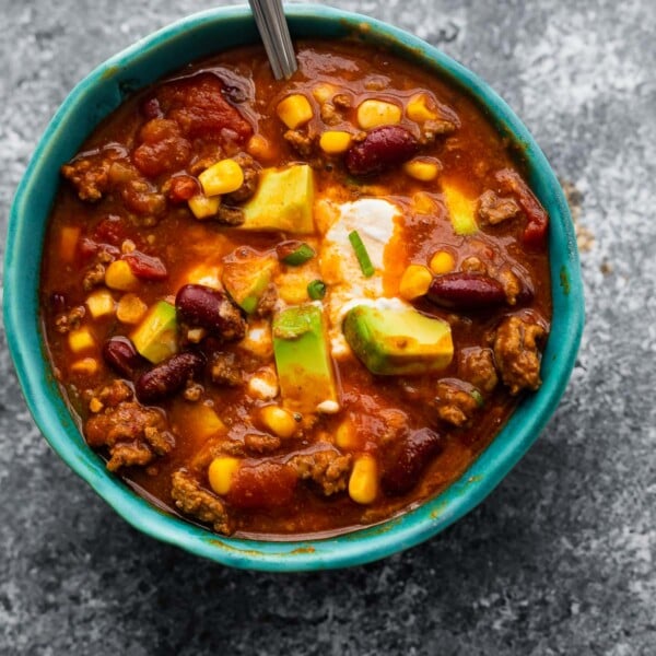instant pot chili in blue bowl garnished with sour cream, cheese and avocado