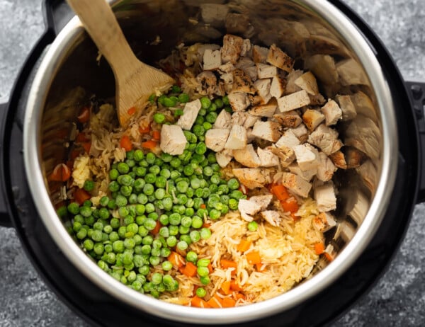 overhead view of fried rice topped with peas and chicken in instant pot