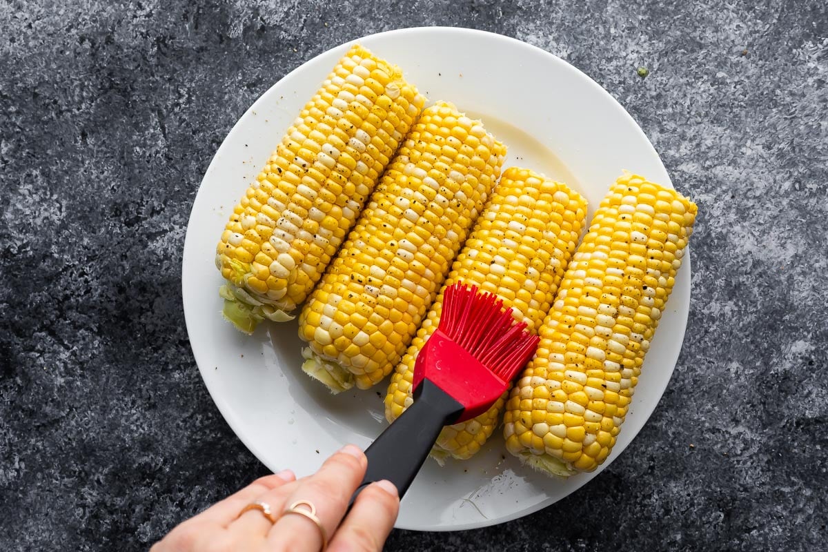 brushing olive oil onto corn on the cob using a silicone brush