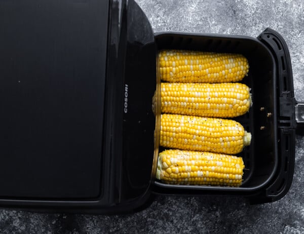 overhead view of four ears of corn in the air fryer basket (before cooking)