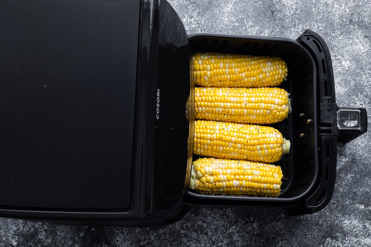 overhead view of four ears of corn in the air fryer basket (before cooking)
