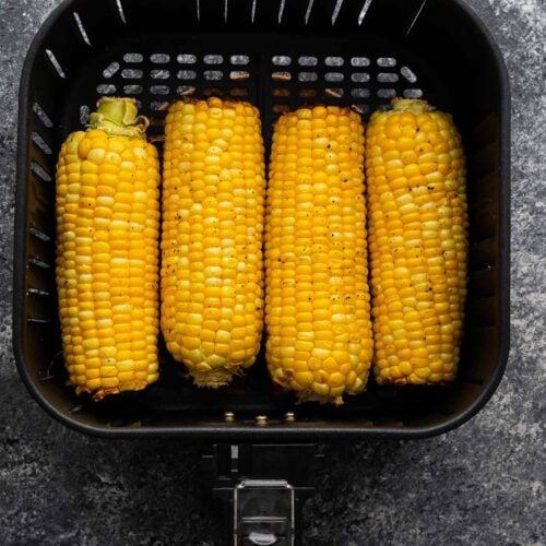 overhead view of four ears of corn in the air fryer basket (after cooking)