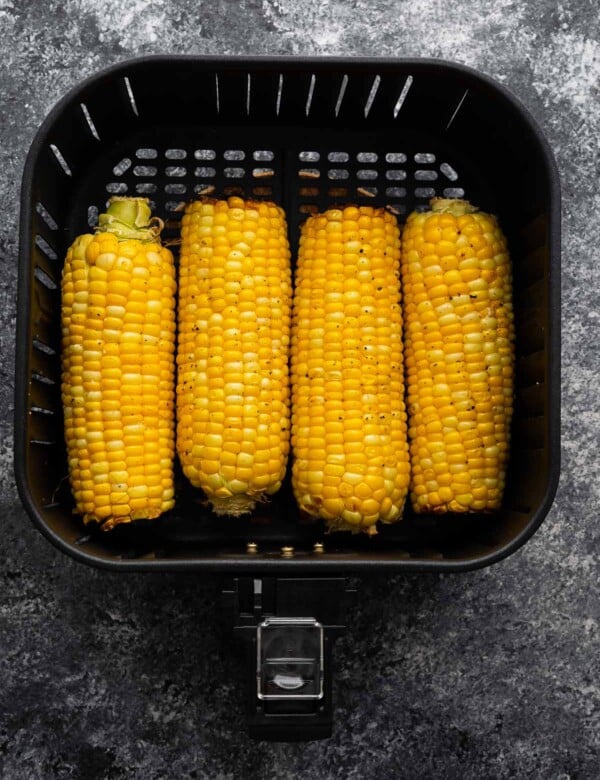 overhead view of four ears of corn in the air fryer basket (after cooking)