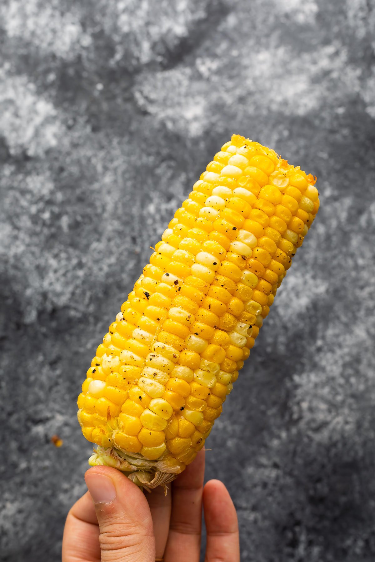 hand holding cooked ear of air fried corn on the cob