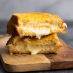 grilled cheese stacked on cutting board revealing melted cheese