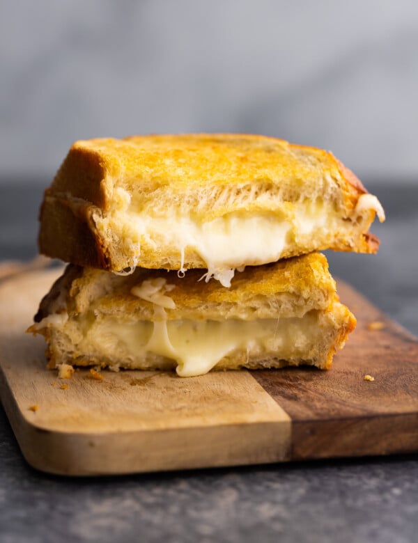 grilled cheese stacked on cutting board revealing melted cheese