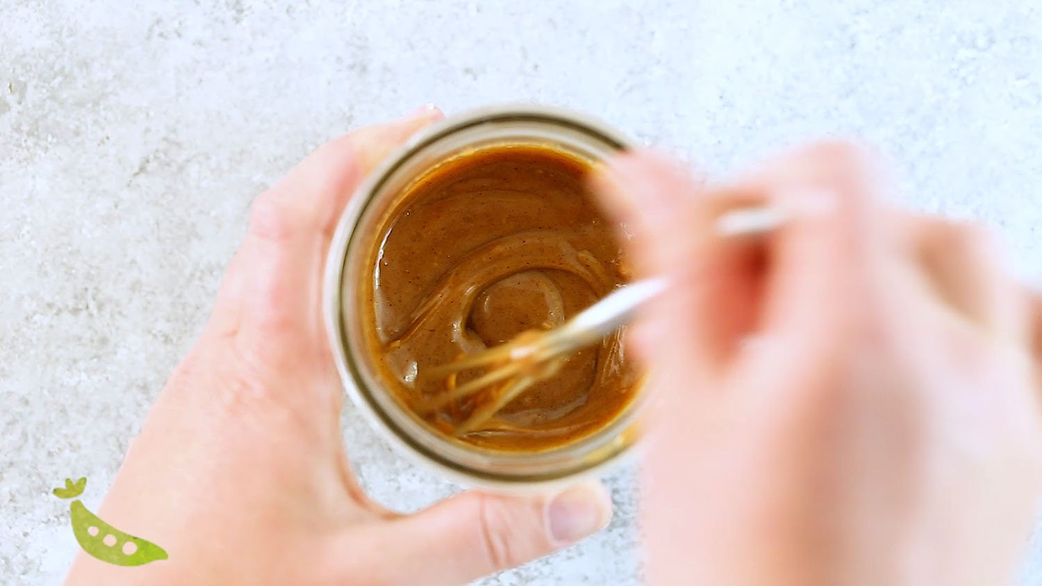 stirring almond butter sauce in jar