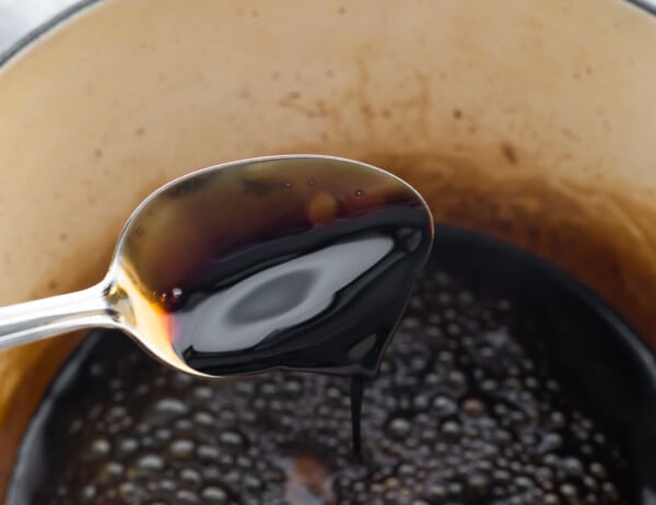spoon tipping balsamic reduction into pot; slightly thickened