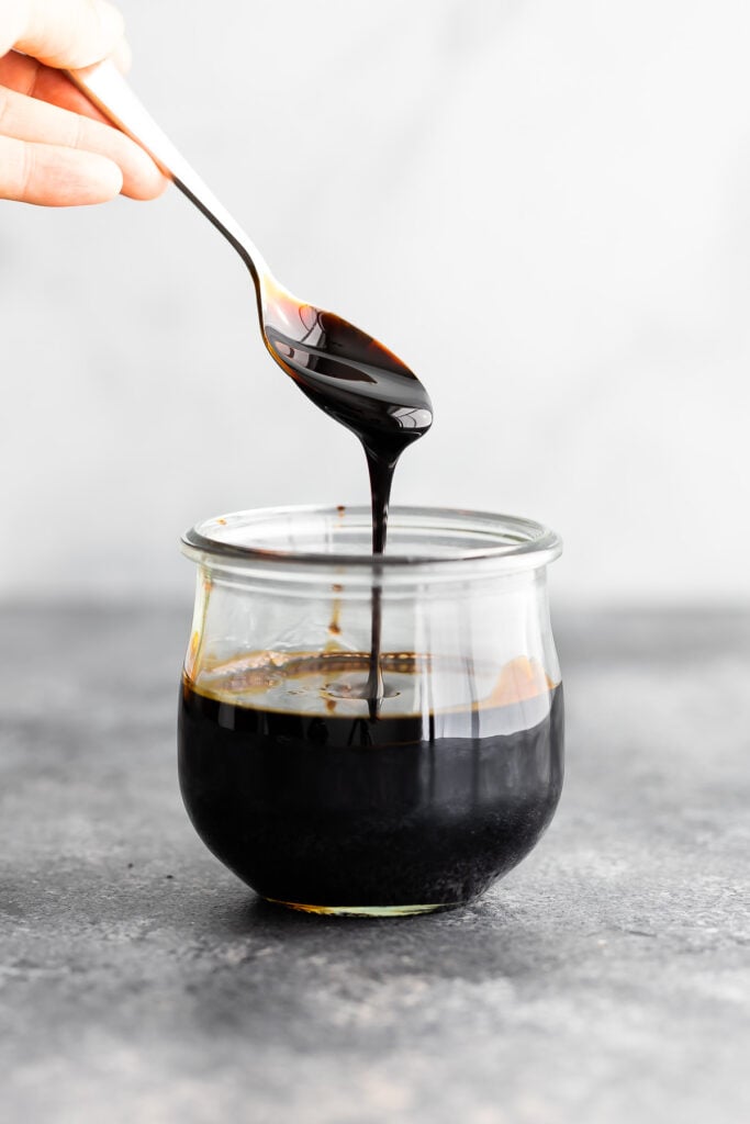 spoon drizzling thick balsamic reduction into a jar