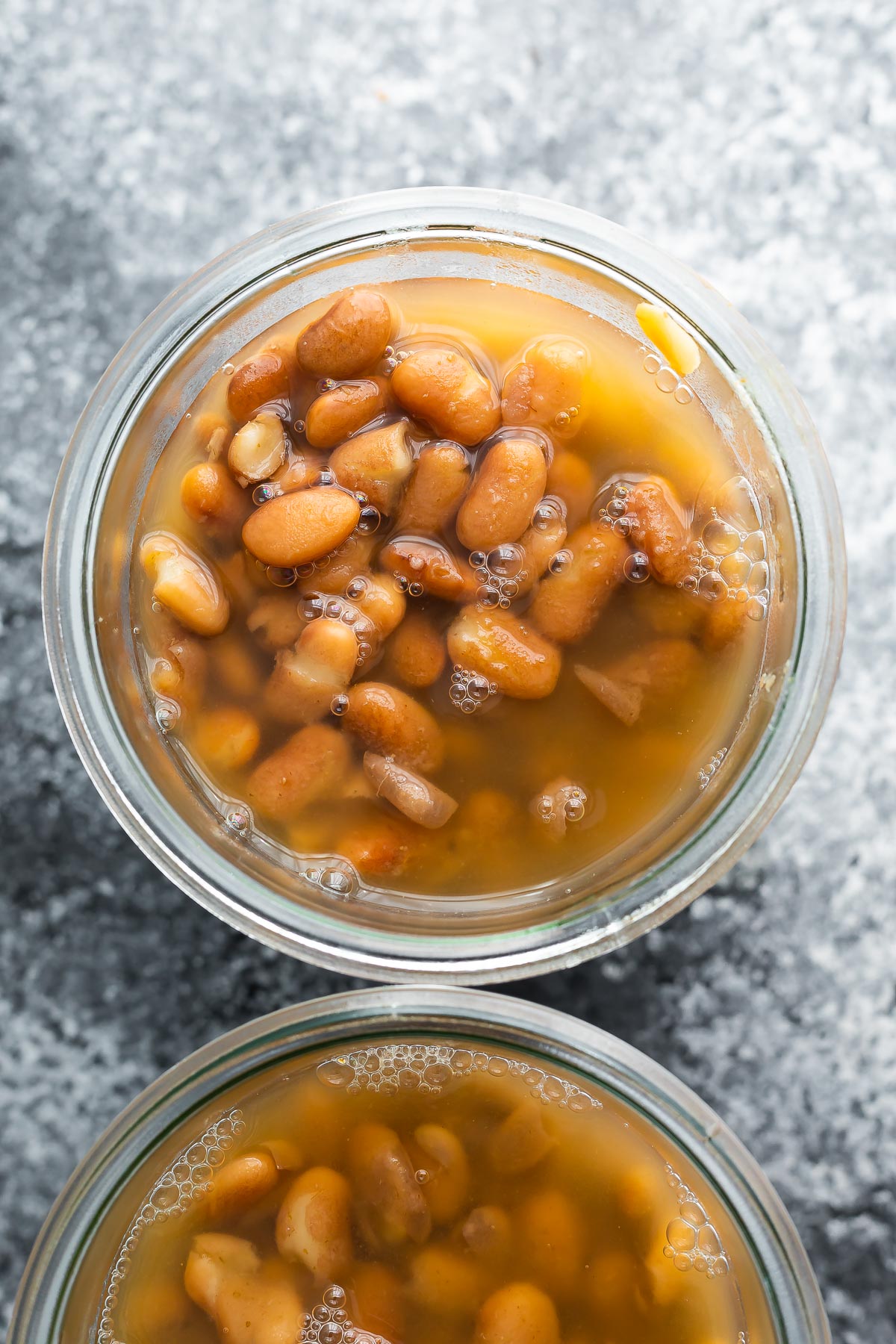 close up shot of cooked pinto beans in jar, covered with cooking liquid