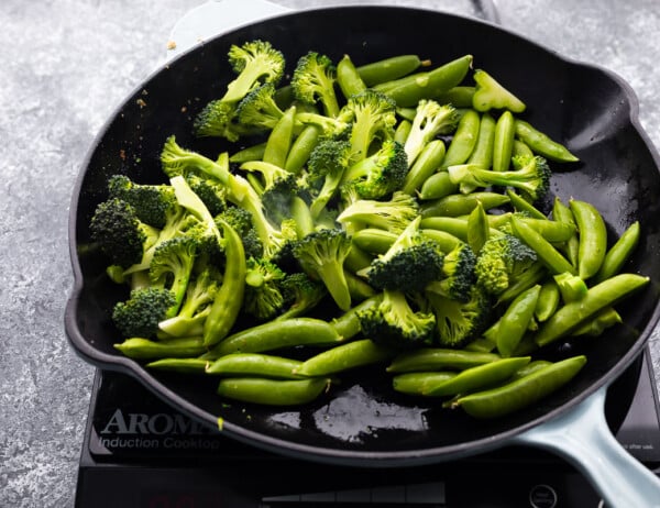 cooking broccoli and snap peas in frying pan