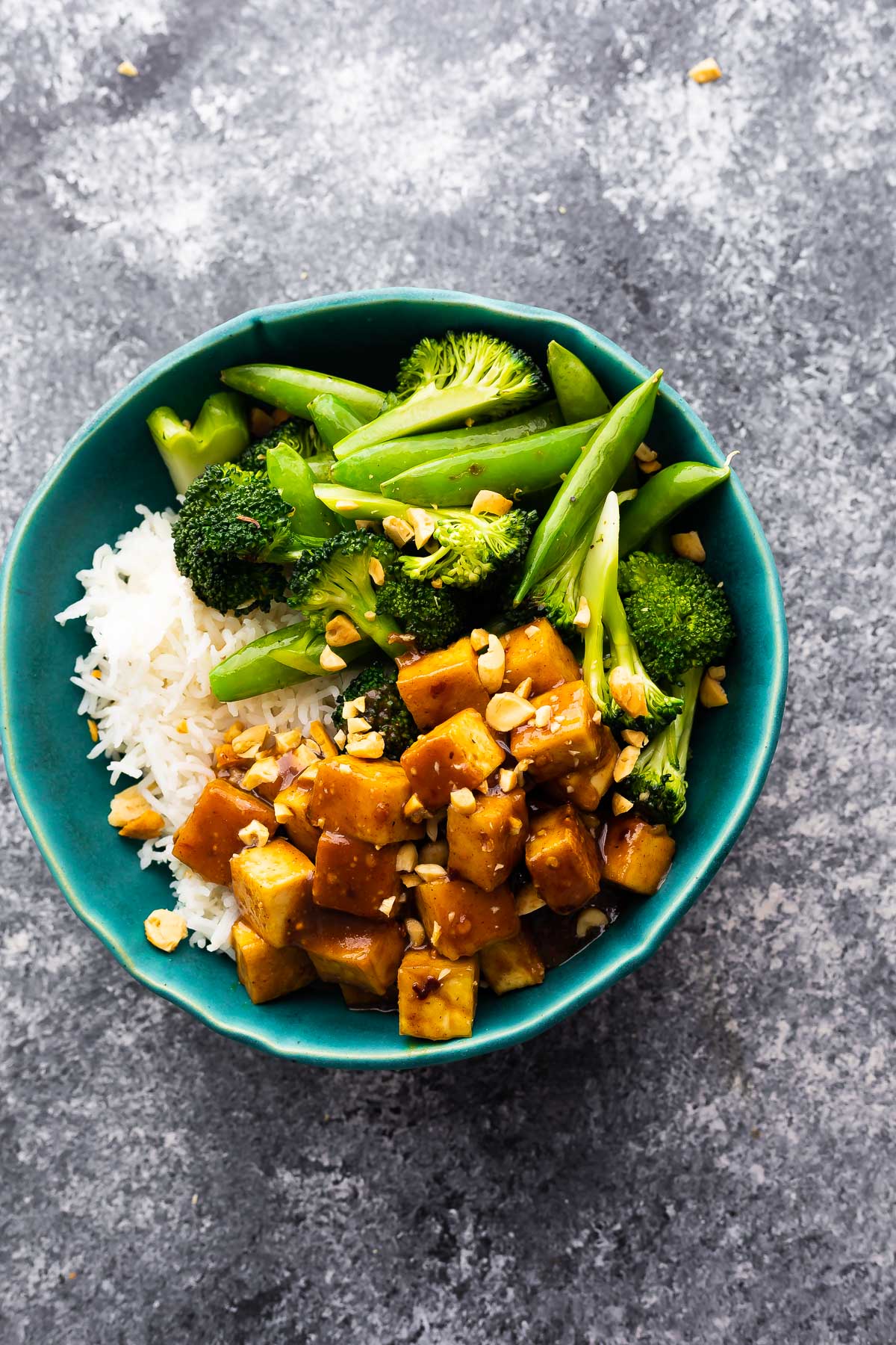 overhead view of peanut tofu in bowl with rice and green vegetables