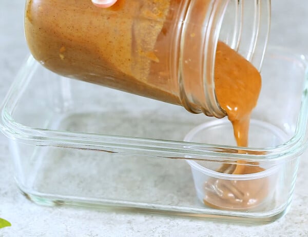 pouring almond butter sauce into a condiment container