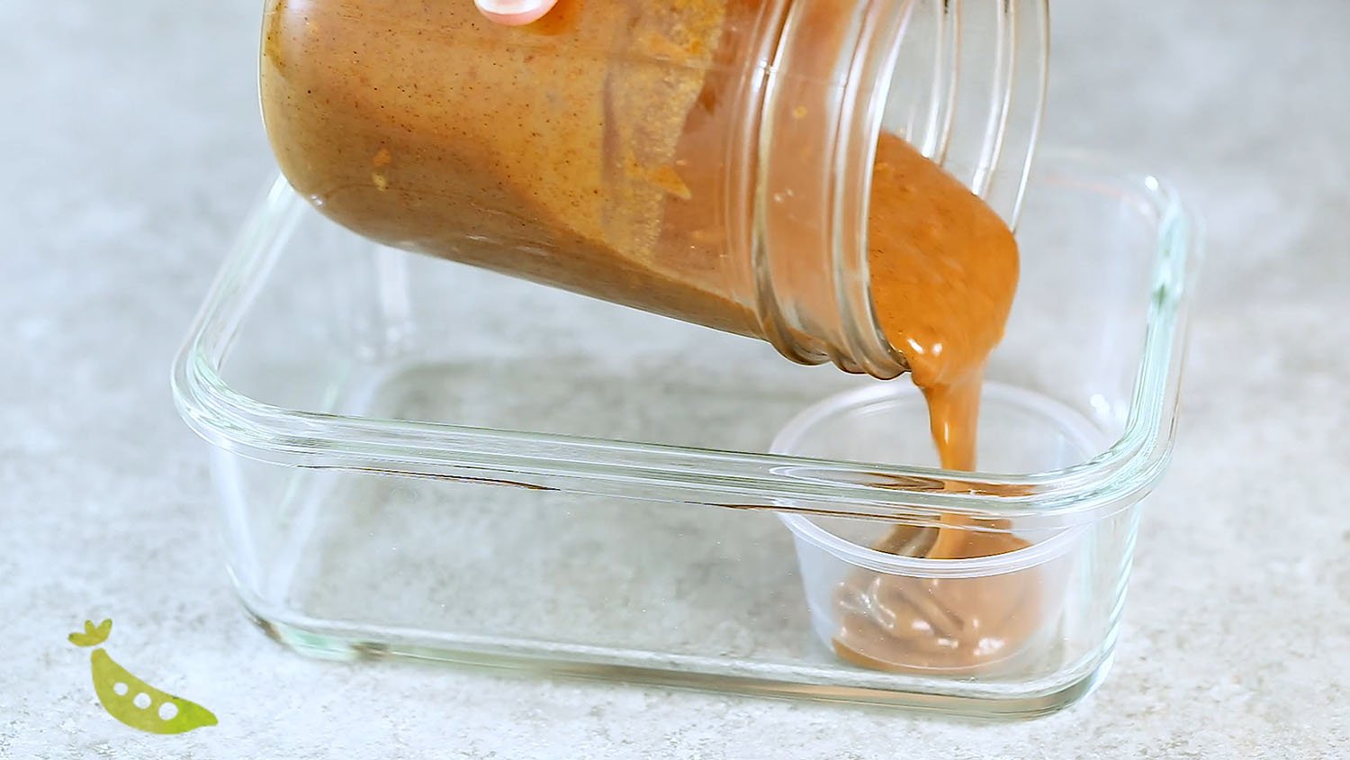 pouring almond butter sauce into a condiment container
