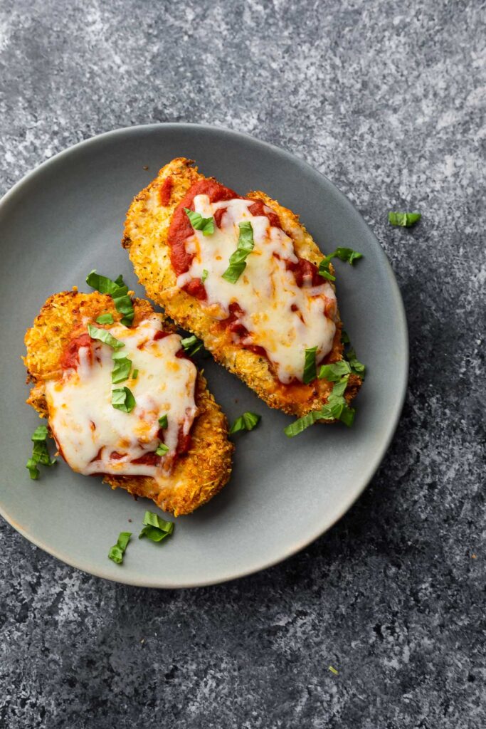 air fryer chicken parm on grey plate sprinkled with basil leaves