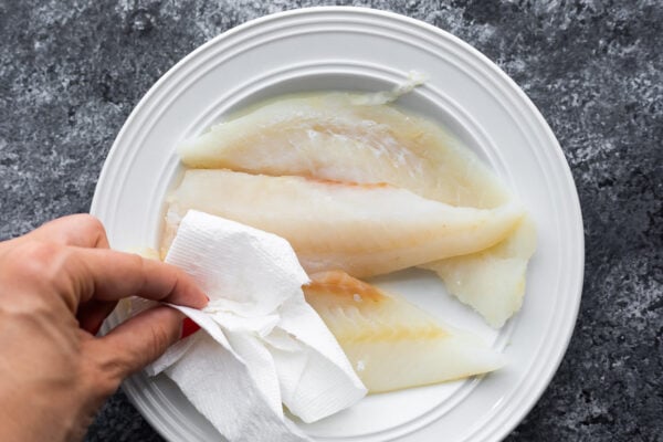 blotting white fish dry with paper towel