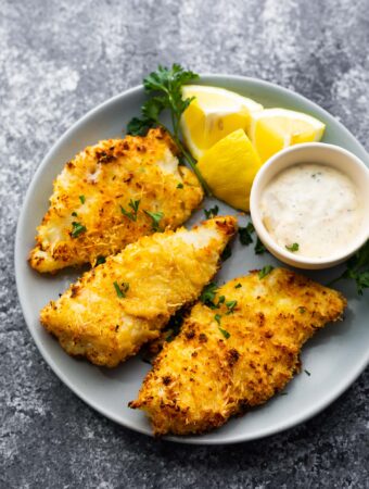 crispy air fryer fish on plate with lemon wedges and tartar sauce