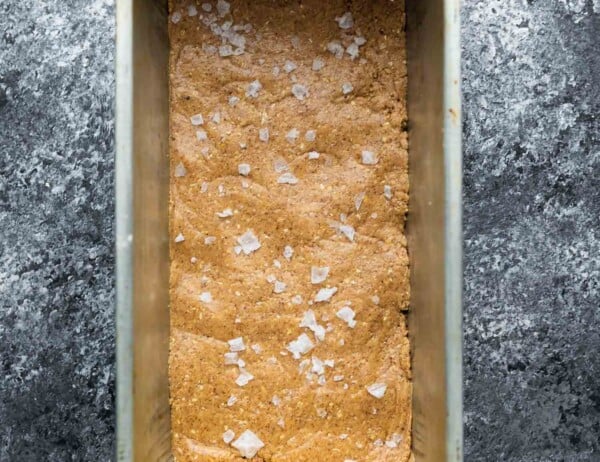 protein bar mixture in loaf pan after pressing and sprinkling with flaky salt