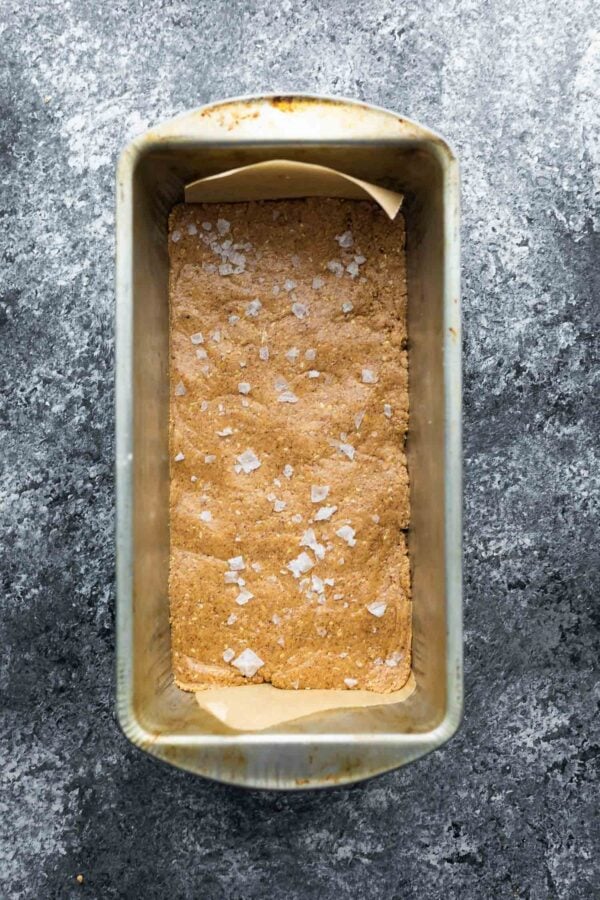 protein bar mixture in loaf pan after pressing and sprinkling with flaky salt