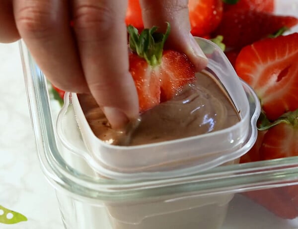 dipping a strawberry into yogurt dip