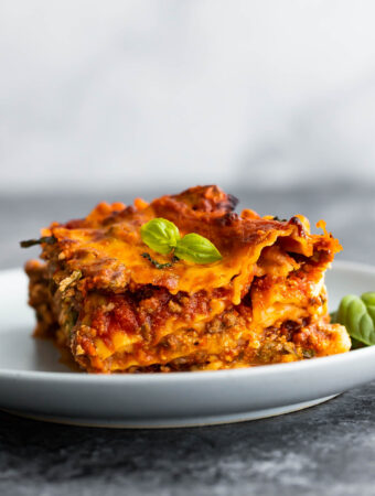 side angle view of slice of lasagna on plate topped with basil