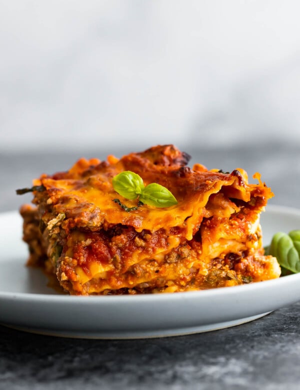side angle view of slice of lasagna on plate topped with basil