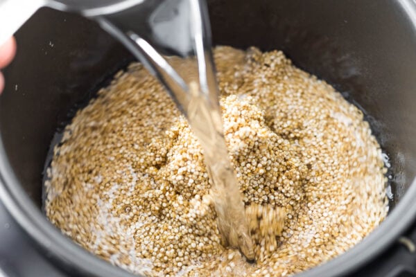 pouring water over quinoa in rice cooker