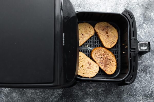 overhead view of uncooked french toast in air fryer basket before cooking through