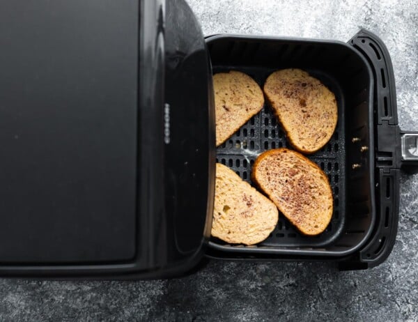 overhead view of uncooked french toast in air fryer basket before cooking through