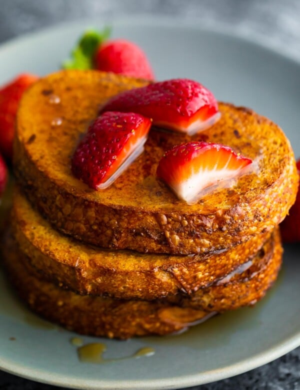 close up view of stack of air fryer french toast with strawberries and syrup