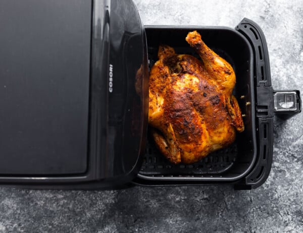 whole chicken breast side up in air fryer basket after cooking through