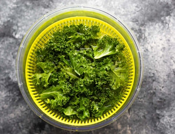 kale in salad spinner filled with water