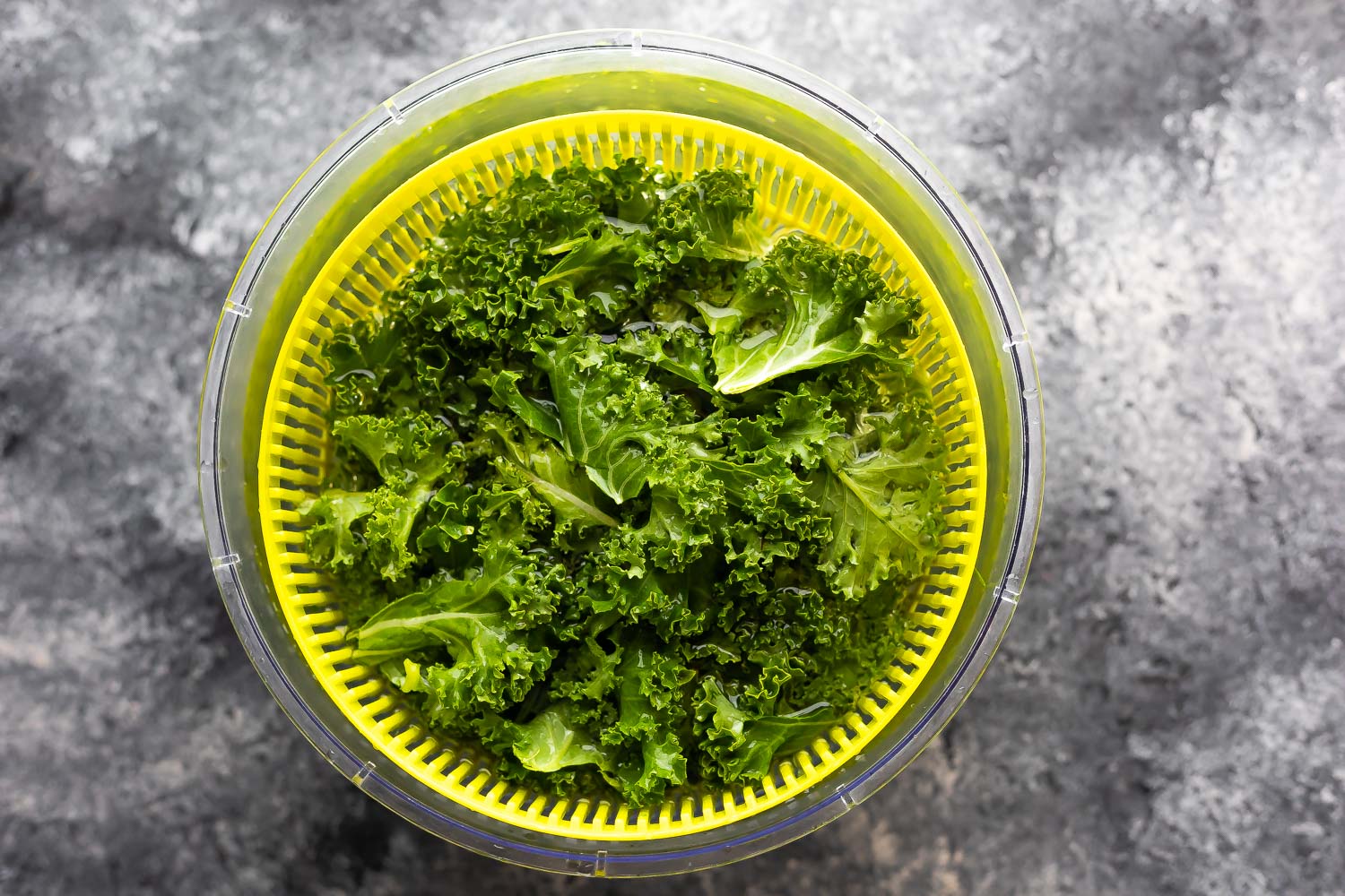 kale in salad spinner filled with water