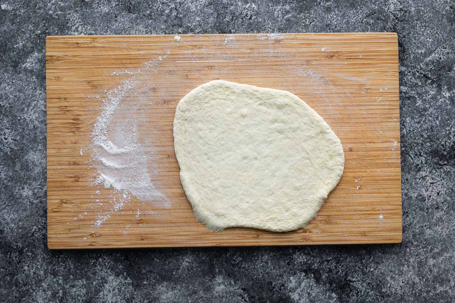 pizza dough rolled out on a cutting board