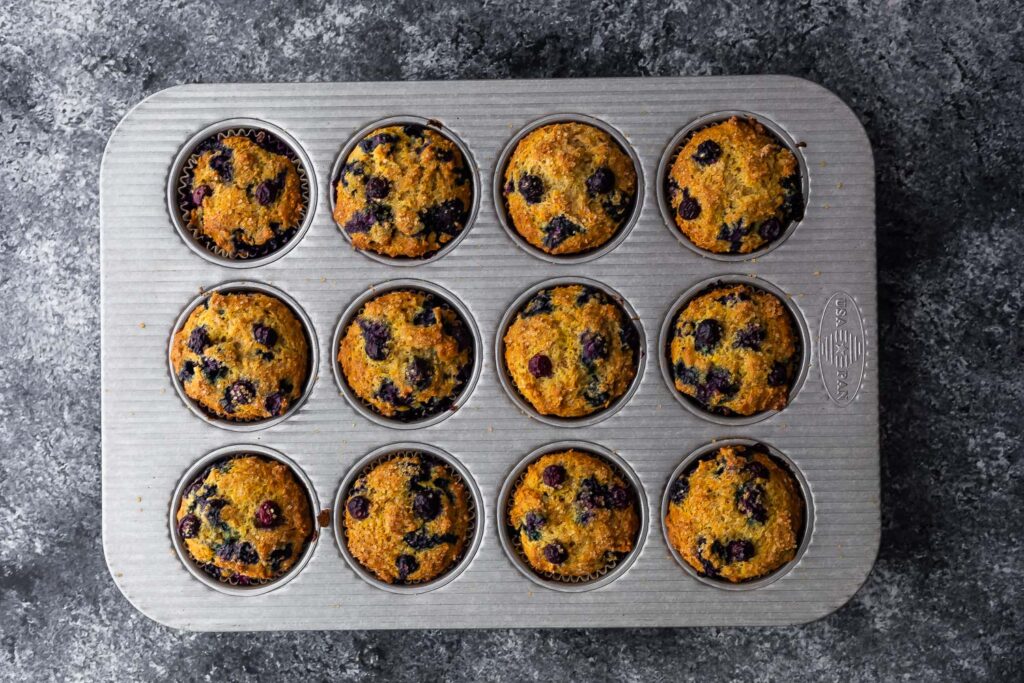 blueberry muffins in muffin pan after baking through- overhead shot