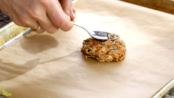 patting the breakfast cookie onto a parchment-lined baking sheet with a spoon